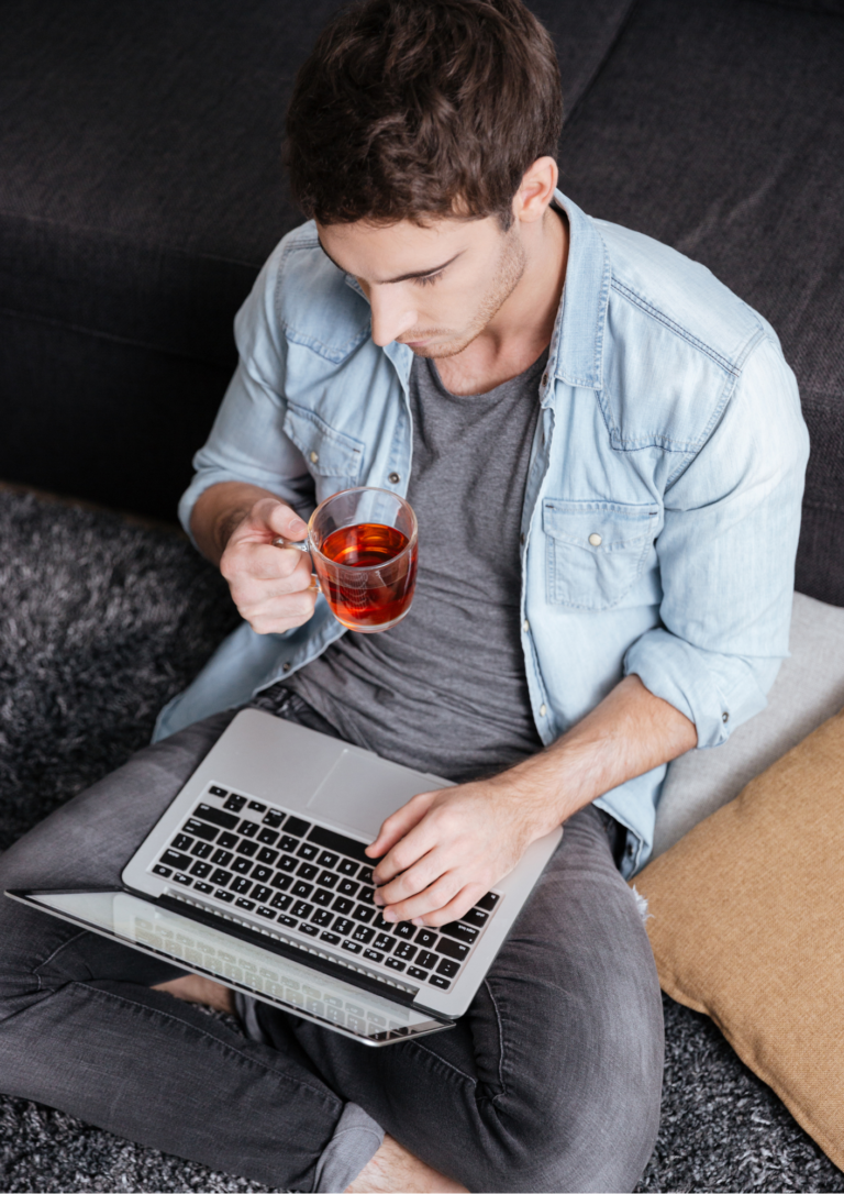 紅茶を飲みながらパソコンを触る男性の画像